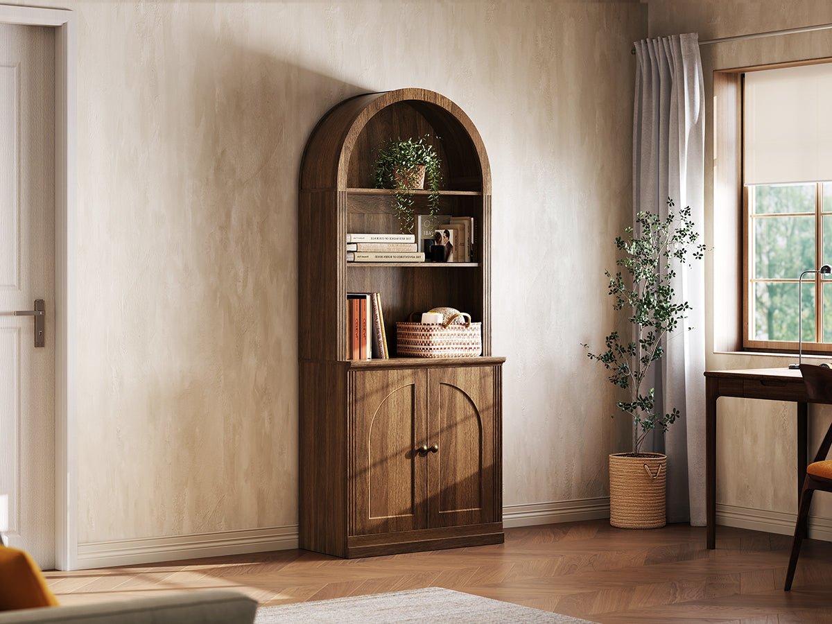Monos walnut tall arch-top cabinet displayed beside a window with books and decor