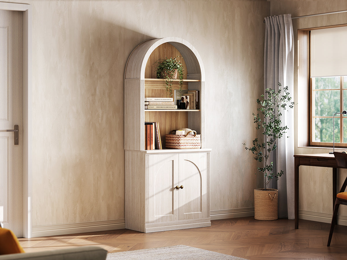 Monos white tall arch-top cabinet displayed beside a window with books and decor