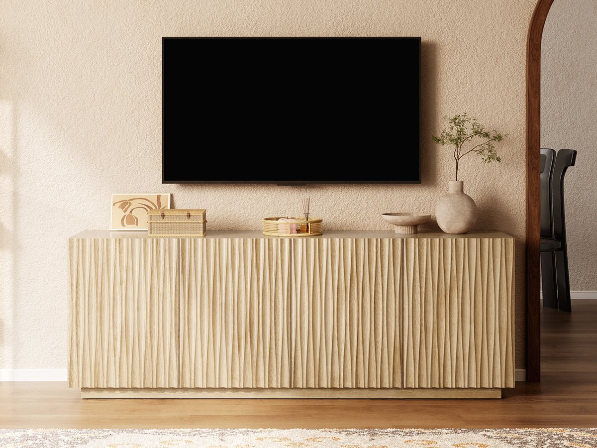 ORYVIA natural wavy fluted storage cabinet used as a TV stand beneath a wall-mounted television in a warm living room
